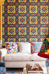 Ornate Amalfi wallpaper with intricate patterns and lemons, a white sofa with embroidered cushions, and a decorative lamp with rich colours.