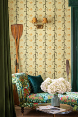 Close-up of yellow wallpaper with vertical green vines and orange fish motifs, wooden oars, and a floral patterned chaise lounge