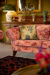 In situ photo of a khaki black and olive cushion on a red and orange velvet sofa.