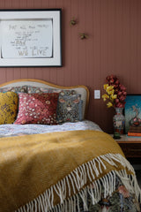 photograph of a serene bedroom with lots of pattern and a William Morris bed cover and featured cushion