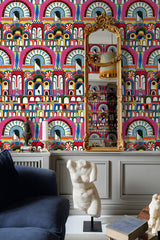 A vibrant room featuring CARNIVALE wallpaper with bold arch patterns, a gold ornate mirror, a blue sofa, and a classical bust