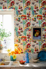 Bright kitchen with vintage-inspired wallpaper featuring market scenes. Kitchen has marble countertops, fresh flowers, bright rustic decor.