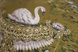 Close up of a fabric with an olive base and white swans