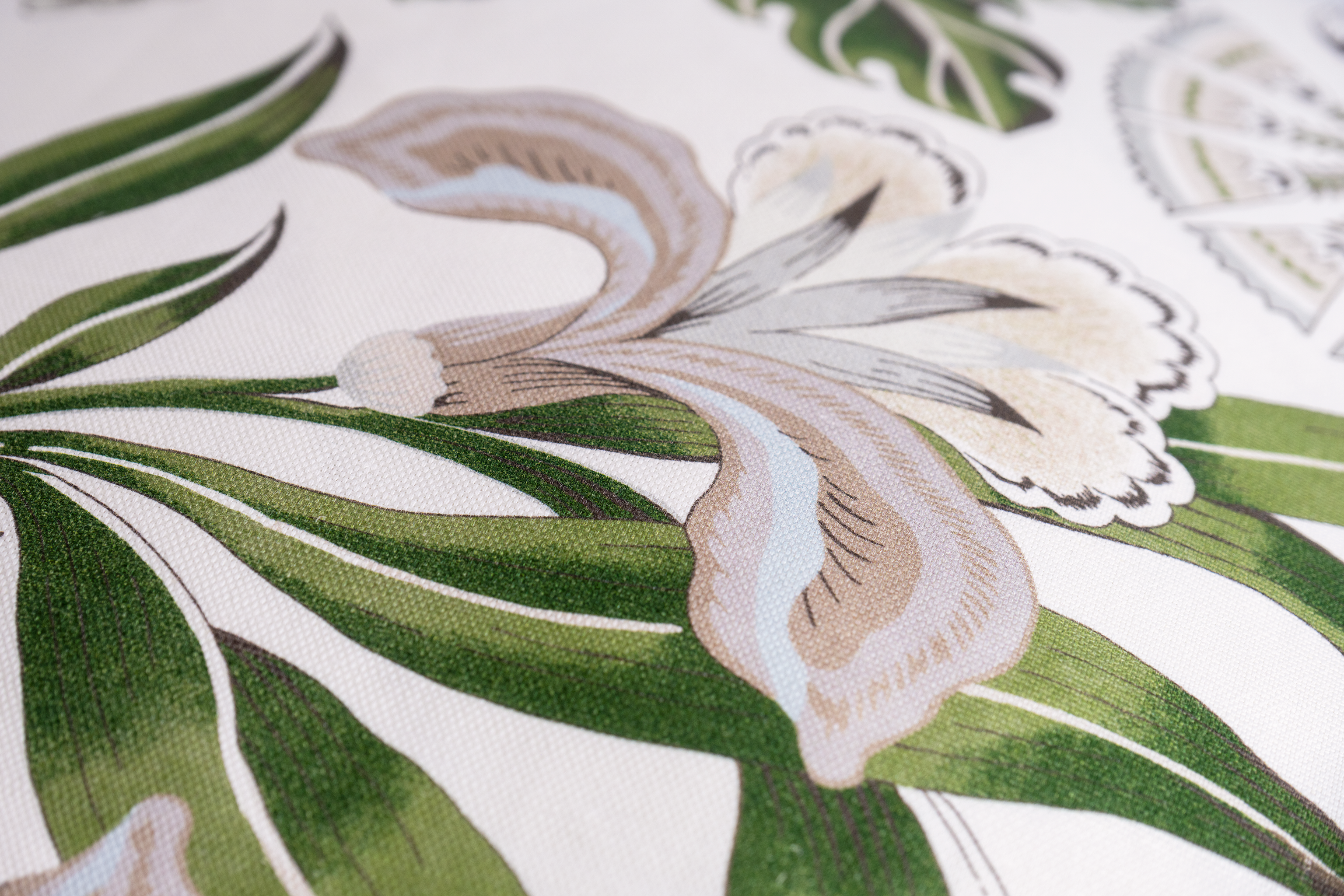 Close-up of a floral design with green leaves and white flowers on a white linen background