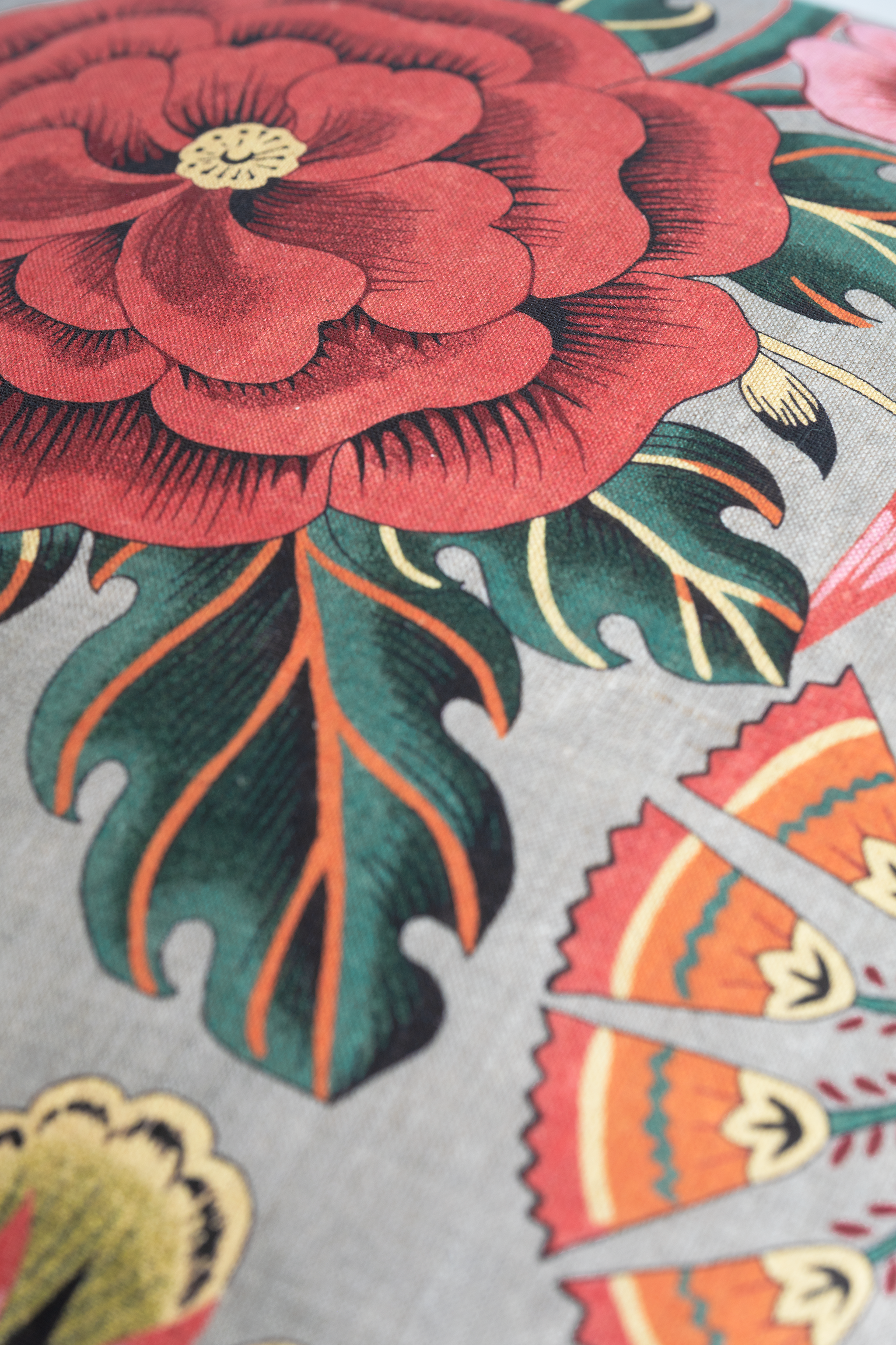Close-up of a colorful floral design with red flowers and green leaves on a gray background.