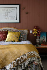 photograph of a bedroom setting with gold silk cushion as the focal point