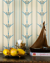 Elegant cream wallpaper with blue botanical stripes behind a rustic vignette featuring a wooden sailboat, pears, a candle in a brass holder, and books.