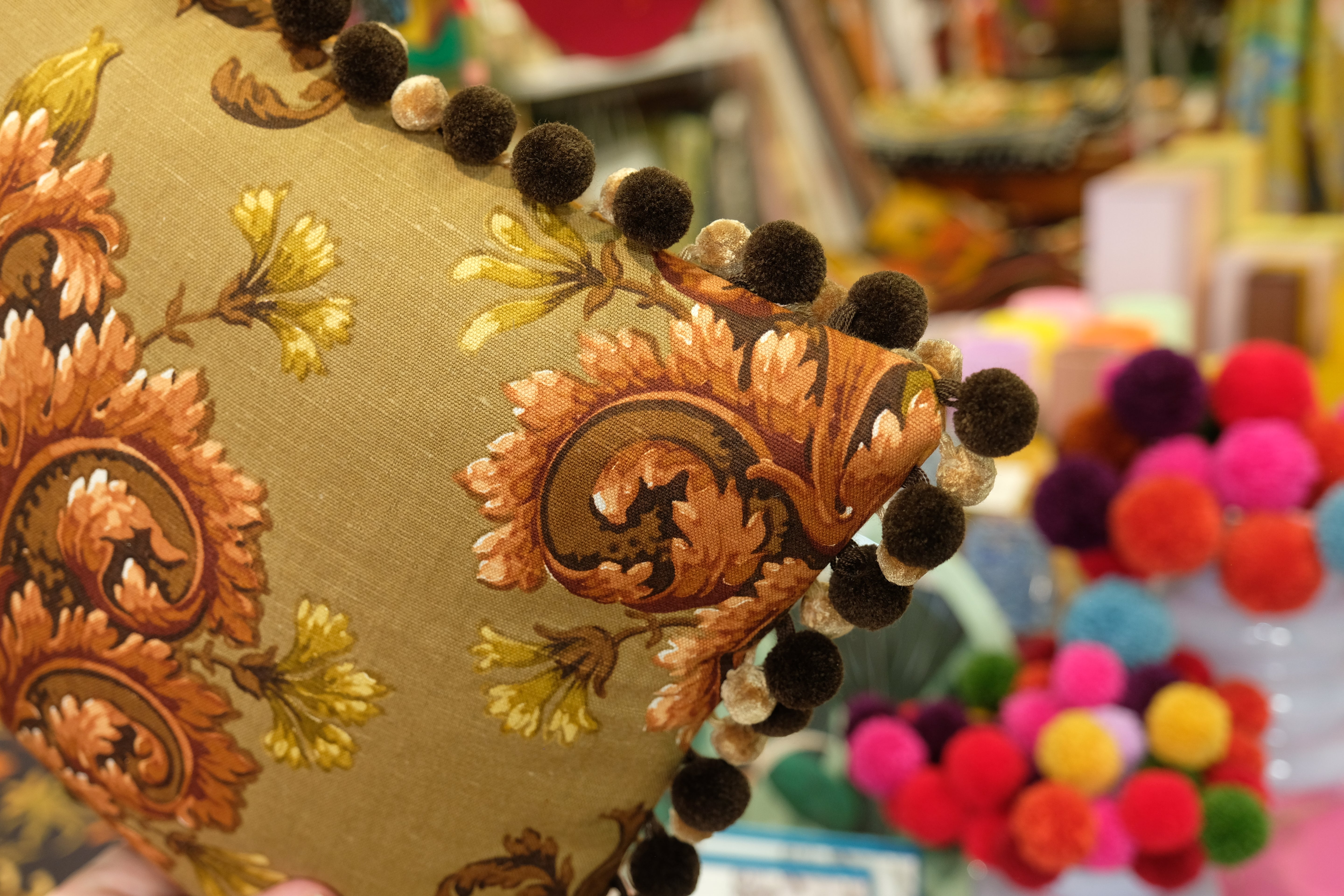 Decorative pillow with intricate patterns and pom-pom trim in a colorful setting