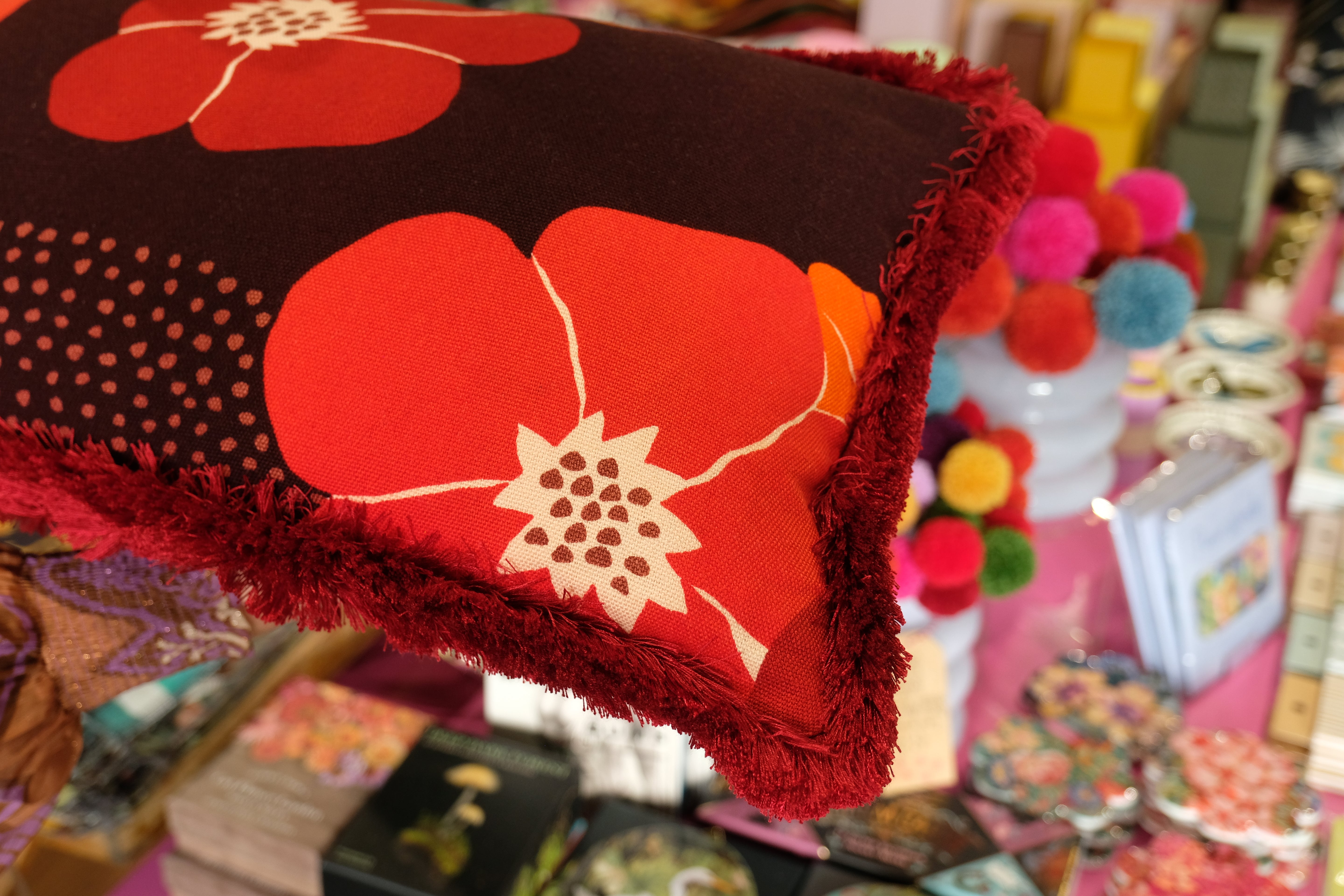 Floral-patterned fabric with red flowers on a dark background, displayed against a colorful background.