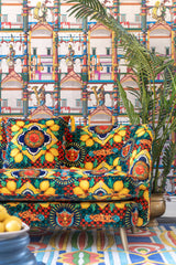 Opulent living space with intricate EL CIRCO wallpaper, a richly patterned sofa with lemon motifs, a tropical plant, and vibrant decor.