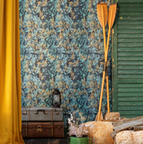 A rustic setting with leafy-patterned wallpaper in blue and gold tones, wooden oars, vintage trunks, a lantern, and hay bales with cozy decor accents