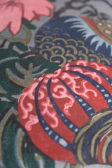 Close up of a floral linen featuring flowers in grey pink red navy and aquamarine.