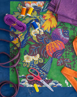 Colorful fabric with sewing supplies on a blue background