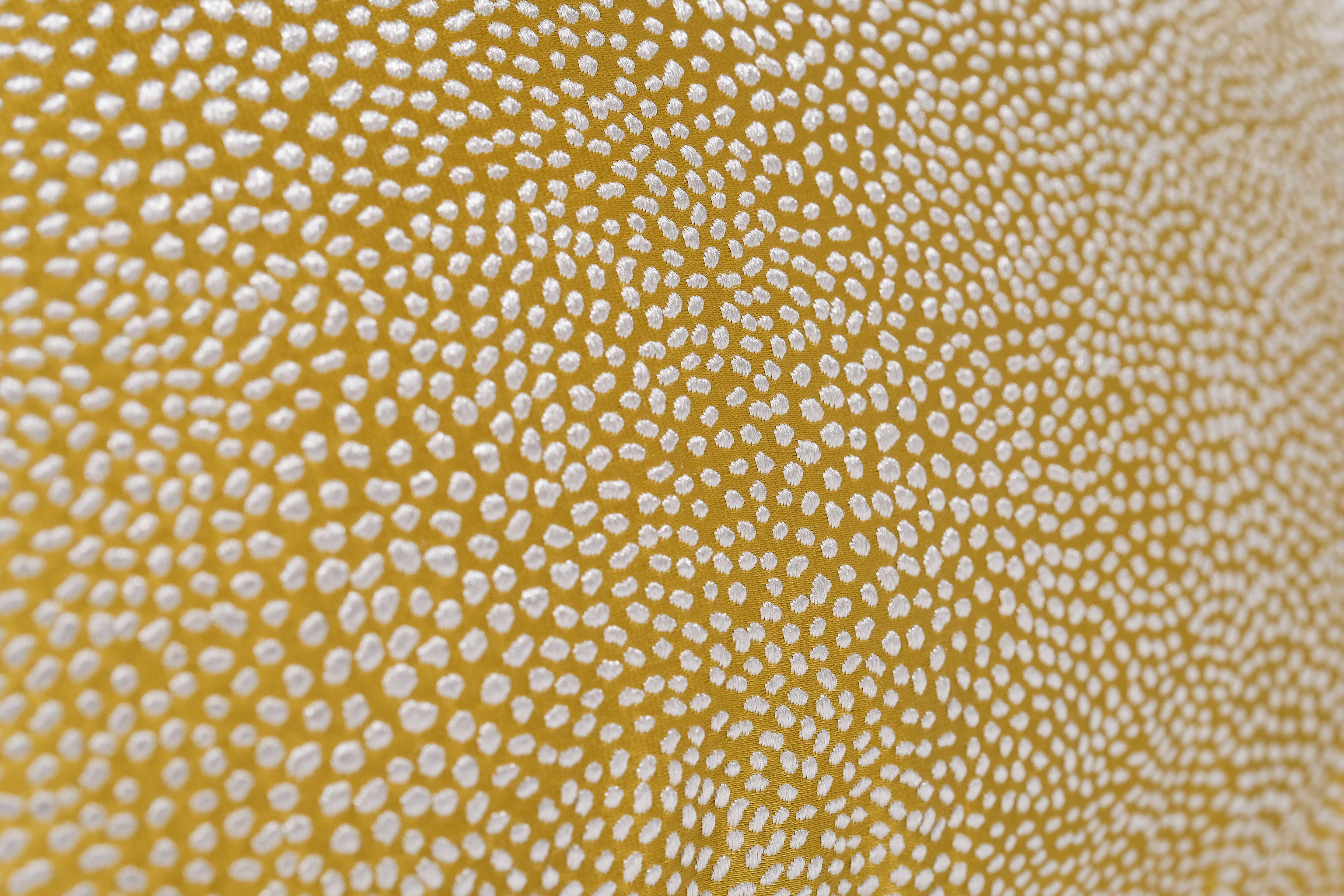 Close-up of a textured yellow fabric with white pattern