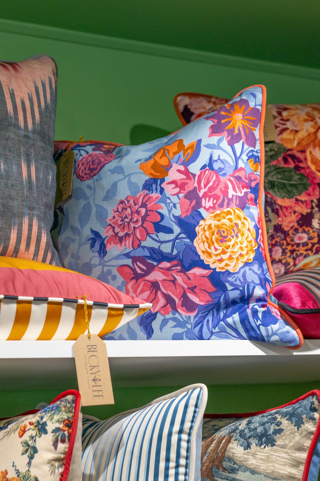 Colorful floral pillow on a shelf with other decorative pillows.
