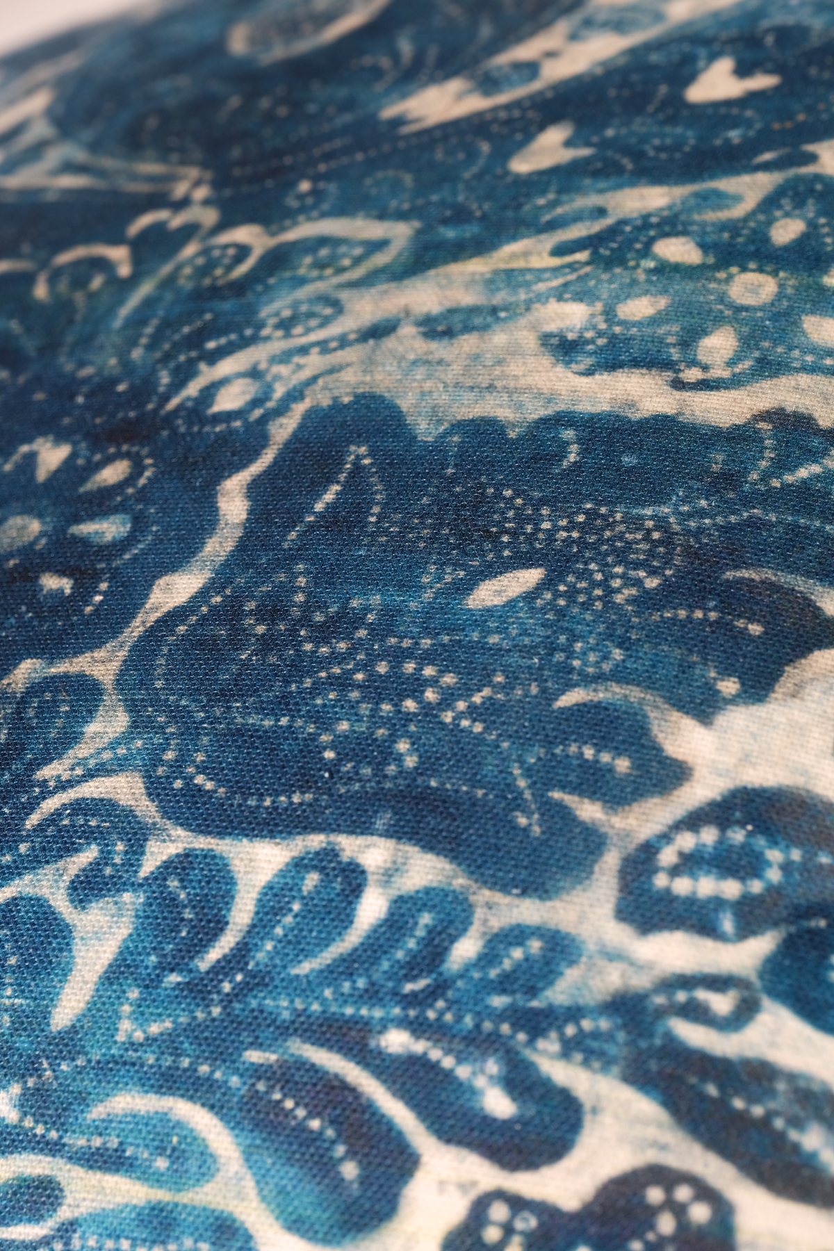 A close-up of a blue and white patterned fabric with a wave-like design, showing the textile texture in detail.