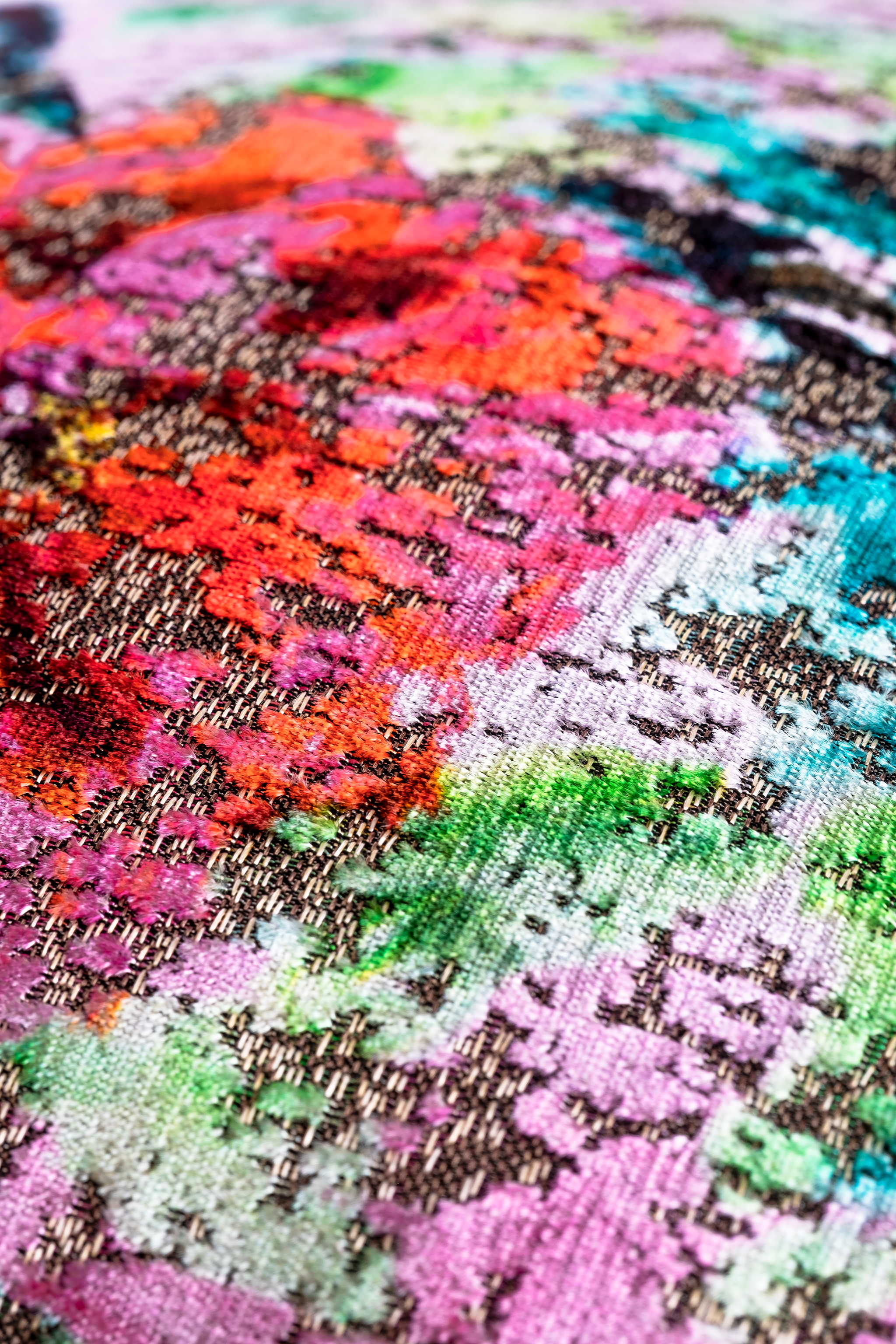 close up of a colourful oriental floral velvet cushion in pinks and greens