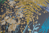 Close up of a printed fabric with botanical silhouettes in multiple colours on a grey background