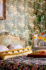 Vintage-inspired bedroom with floral café-scene wallpaper - LA BRASSERIA Fern, an ornate headboard, layered patterned bedding, decorative pillows, and fresh flowers.