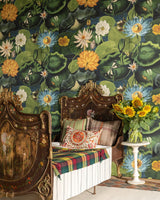 A vintage bedroom with ornate wooden beds, floral bedding, and vibrant water lily wallpaper. A vase of sunflowers adds a cheerful touch to the elegant space