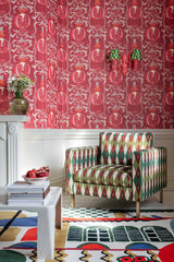 Elegant room with MELAGRANATA wallpaper featuring ornate pomegranate motifs, a geometric armchair, a colorful rug, and decorative accents.