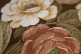 Close up of a floral printed cotton with large scale roses in autumn colours