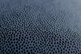 Close-up of a textured dark blue fabric with a black raised spot