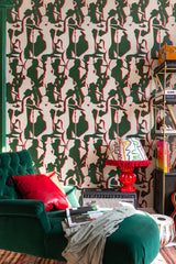 Graphic green and red silhouette wallpaper with musicians playing instruments, paired with a green velvet armchair, red pillow, and a patterned lamp.