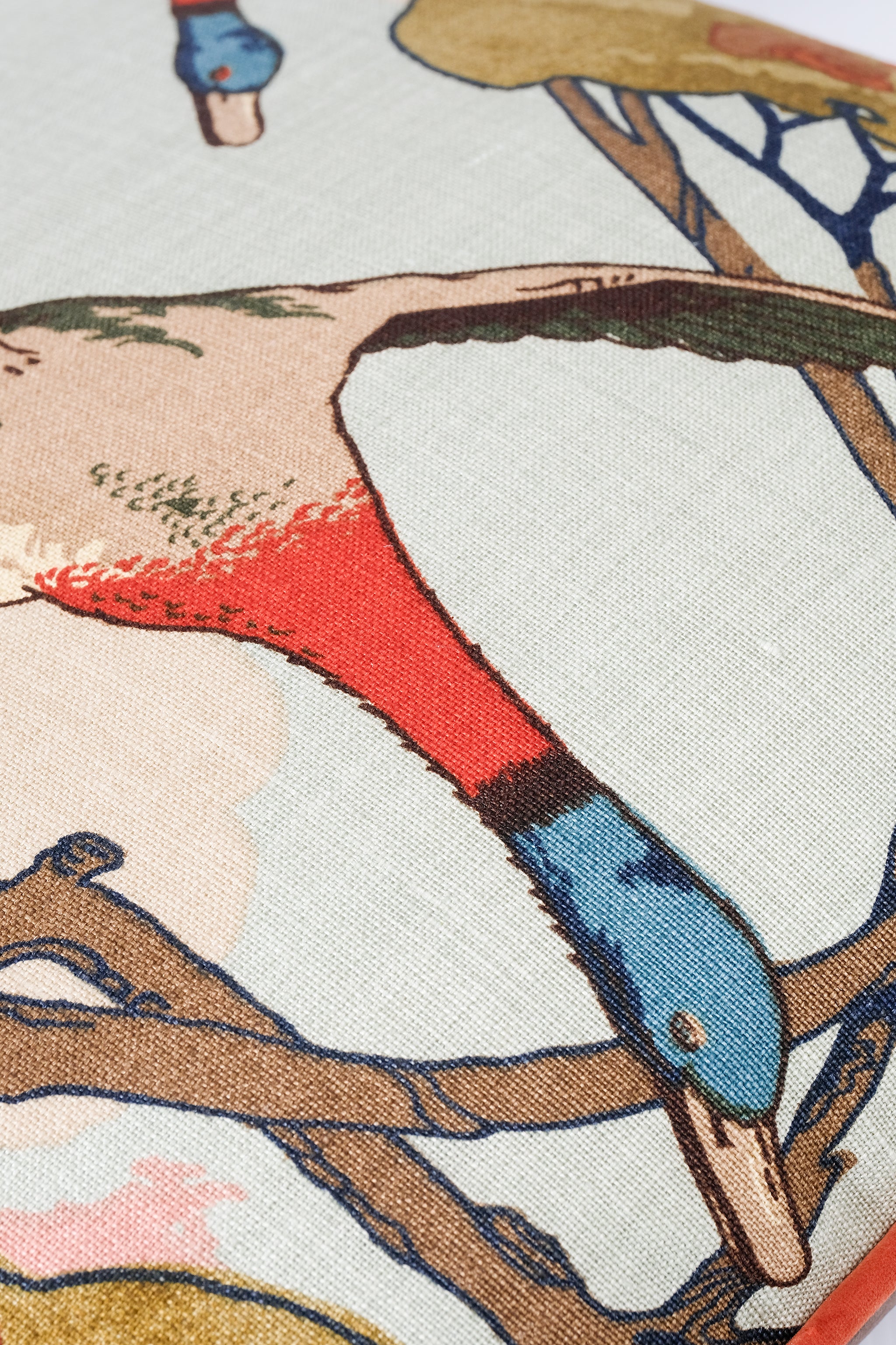 Close-up of a fabric with a colorful bird design on a branch.