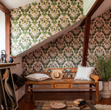 Cozy attic nook with vintage botanical wallpaper featuring green pears and white blossoms. Styled with a wooden bench, soft pillows, and rustic decor.