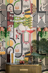 Close-up of PIACERI MONDANI wallpaper with bold geometric patterns, vintage accents, green sconces, and a gold-toned sideboard.