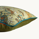 Side photo of a cushion with peacocks and cherry blossoms with an oriental decorative border and teal piping.