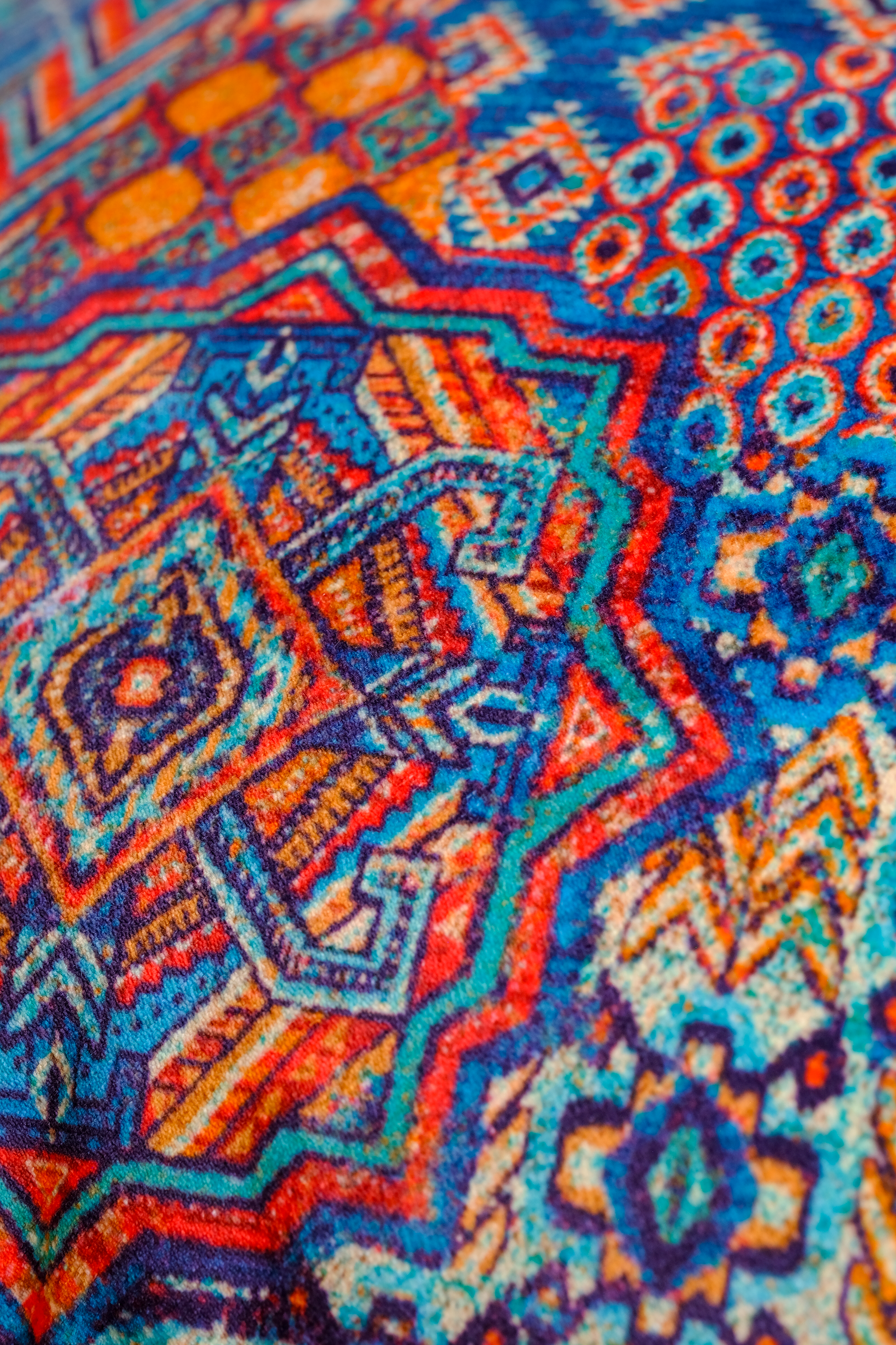 Close up of a colorful Persian geometric velvet in orange, cobalt and turquoise