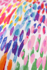 Close up of a fabric with a colourful abstract pattern of painterly dashes .