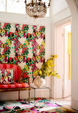 Vibrant wallpaper with classical bust illustrations, bold geometric shapes, and tropical foliage in a stylish, eclectic interior