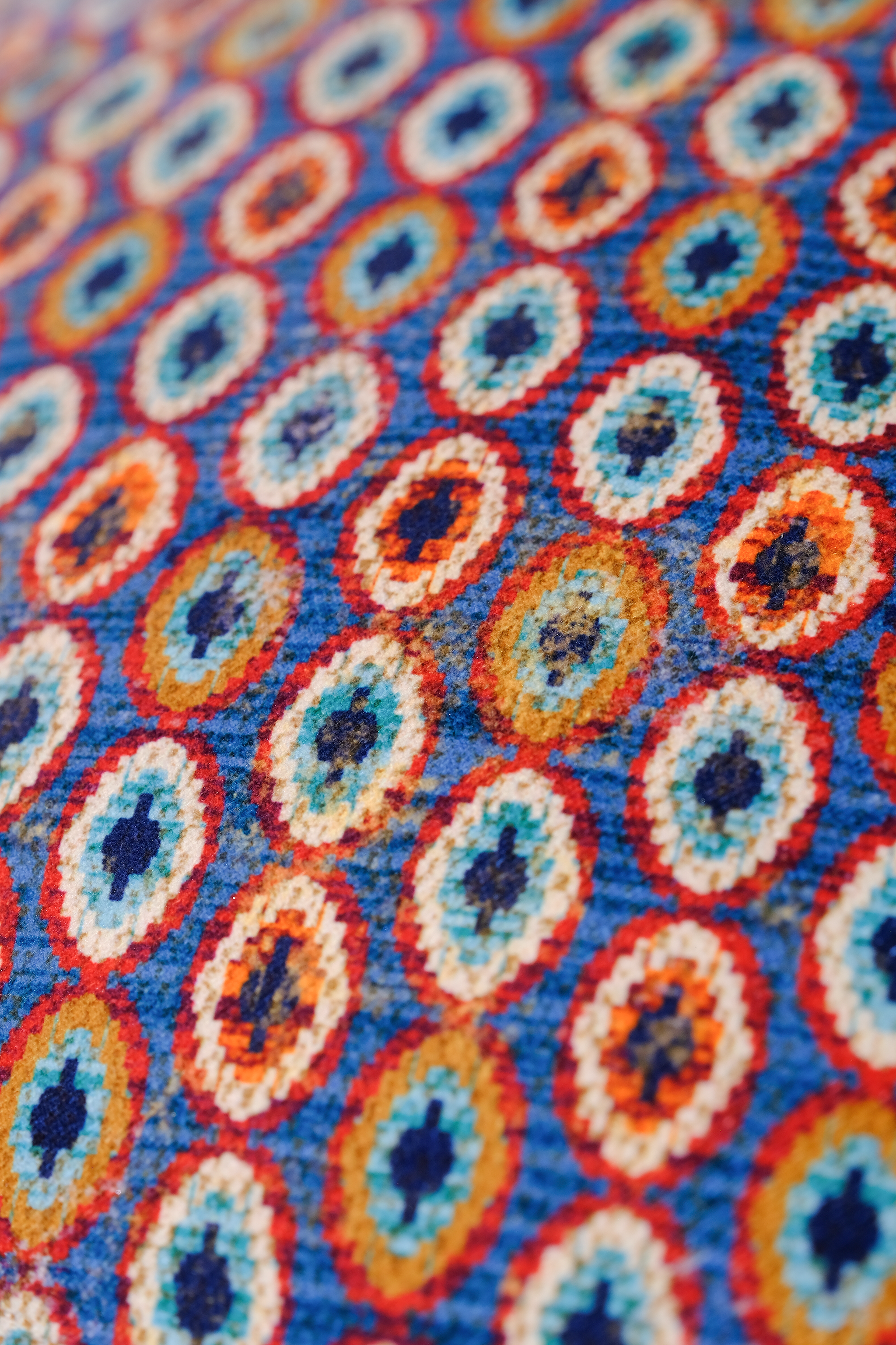 Close up of a velvet with a geometric pattern of oval medallions in blue and brown