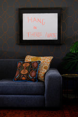 Room setting with wallpaper and a sofa with brightly coloured cushions