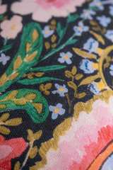 Close-up of a floral fabric pattern with pink, green, and blue colors on a dark background.