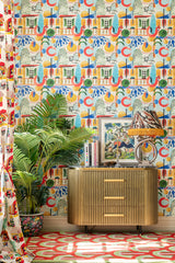 A stylish room with Mind The Gap Veranda wallpaper, a dark wood sideboard, golden accents, potted palm, and framed art creating a sophisticated look