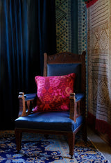Maximalist room setting with a vintage wooden chair with a bright red and pink damask cushion