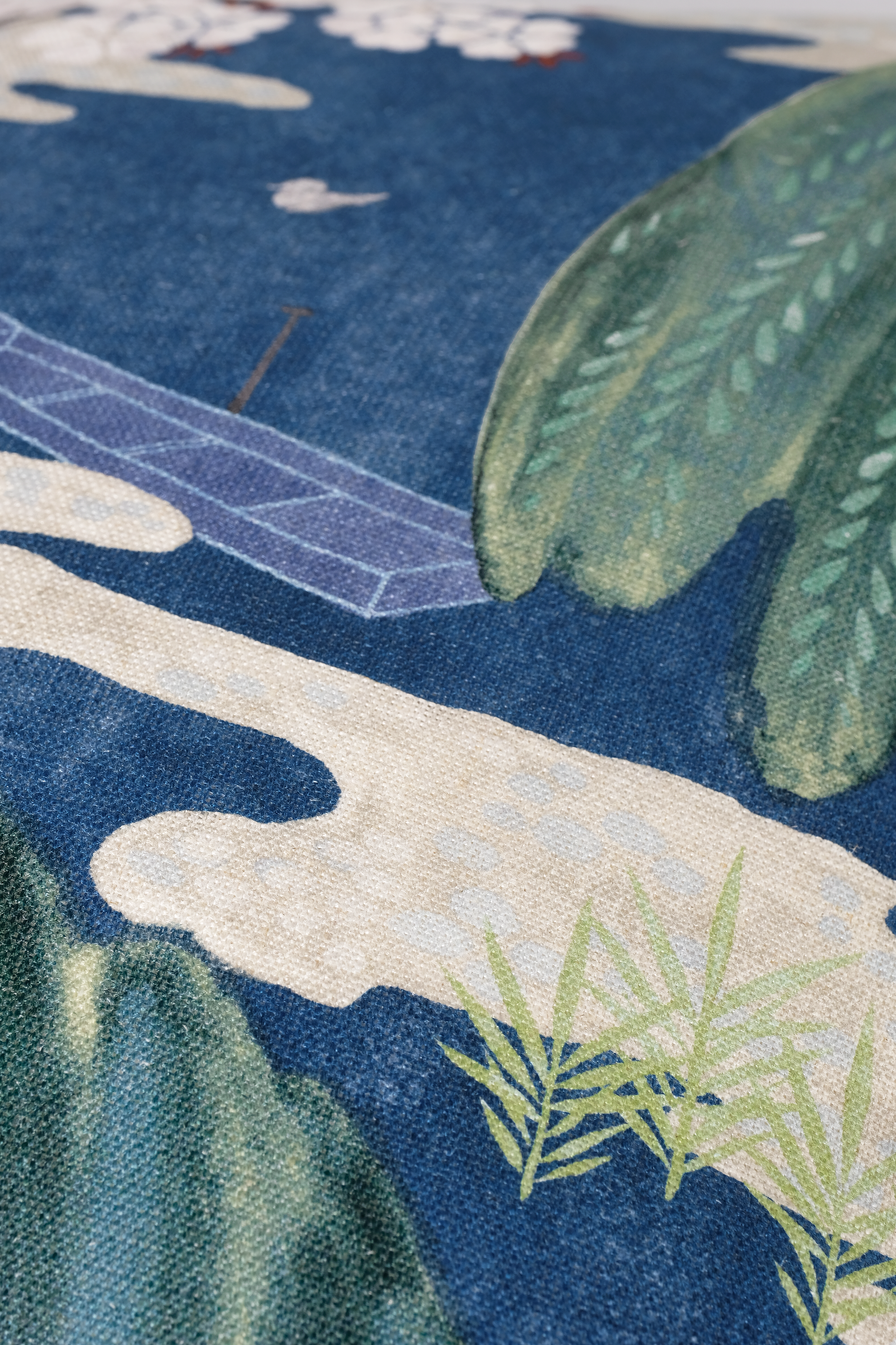Close-up of a Japanese-style textile print featuring a blue ocean scene with white clouds, green foliage, and a pale beige shoreline.