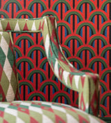 A close-up of a striking red and green patterned wallpaper with an elegant geometric chair in the foreground, creating a rich and eclectic aesthetic