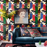Living room with bold geometric wallpaper, velvet sofa with floral cushions, yellow flowers in vase, and portrait artwork on a console table.