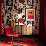 Room with abstract jazz-inspired wallpaper in red, black, cream, a rattan sideboard, red chair, and framed artwork.