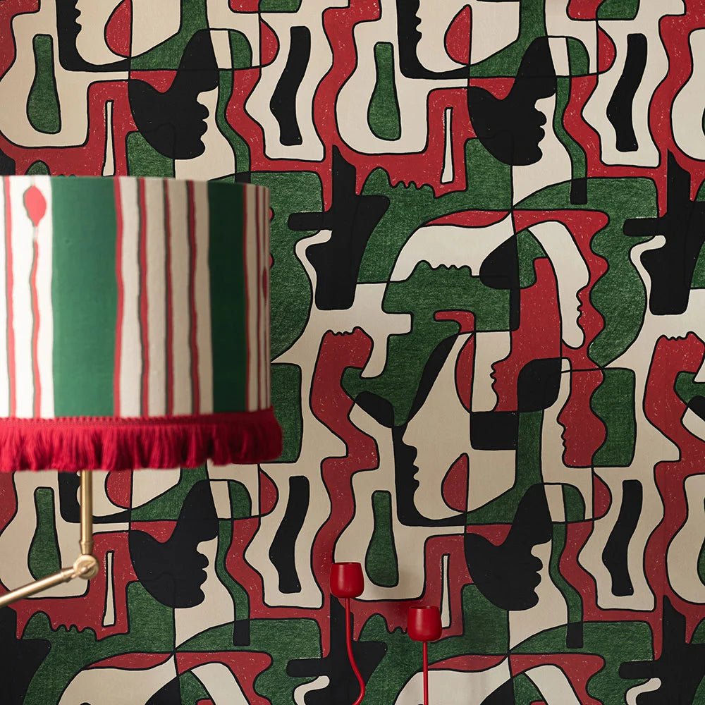 A green, red and black abstract wallpaper with overlapping silhouette faces and geometric shapes, creating a bold statement wall.