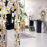A modern interior featuring gold and black abstract face wallpaper on a partition, with sculptural decor and a sleek black console table in the background.
