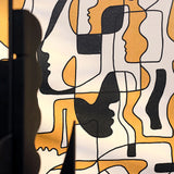 A close-up of a gold and black abstract wallpaper with overlapping face silhouettes and flowing shapes in a modern, artistic design