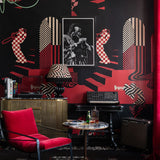 Eclectic music-themed room with red and black checkered wallpaper, red chair, and framed Miles Davis photo.