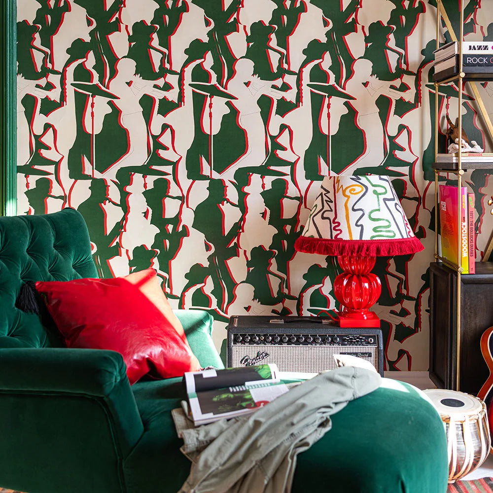 Living room with green armchair, red cushion, and wallpaper of green and red silhouettes of jazz musicians.
