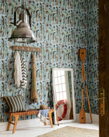 A nautical-inspired entryway with fishing-themed wallpaper, rustic wood bench, striped textiles, oars, and a vintage mirror reflecting a life preserver
